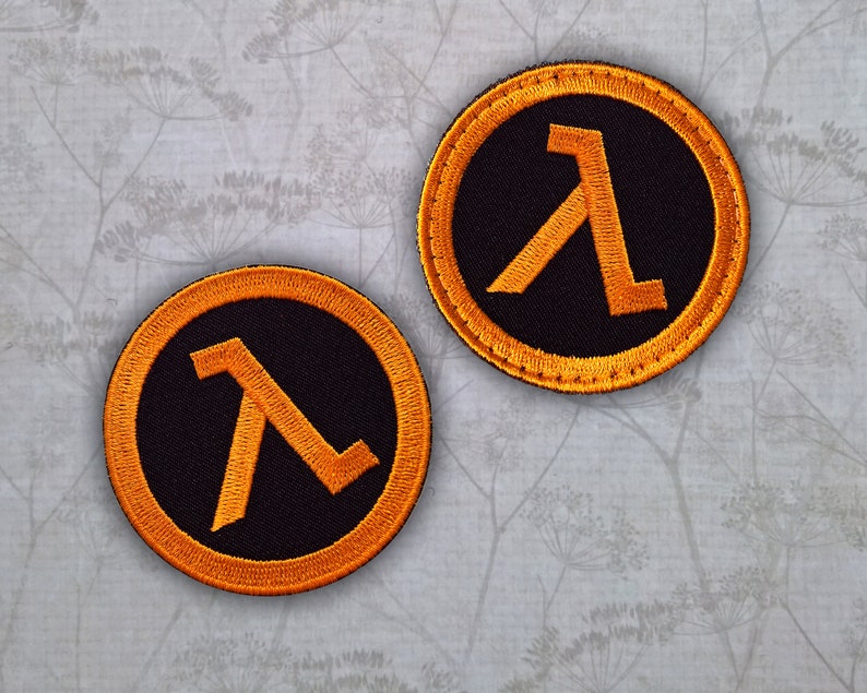 May include: Two black and orange embroidered patches featuring the Lambda symbol from the Half-Life video game series.