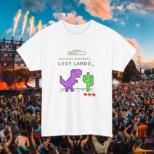 May include: White t-shirt with a pixelated design featuring a purple dinosaur, green cactus, and three red hearts. The shirt has the text "EXCISION PRESENTS... LOST LANDS_" and a loading bar graphic.