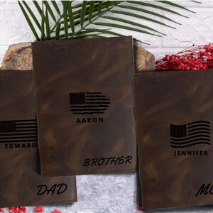 May include: Three brown leather journals with an American flag design and personalized names. The journals are labeled "Dad", "Brother", and "Mom".