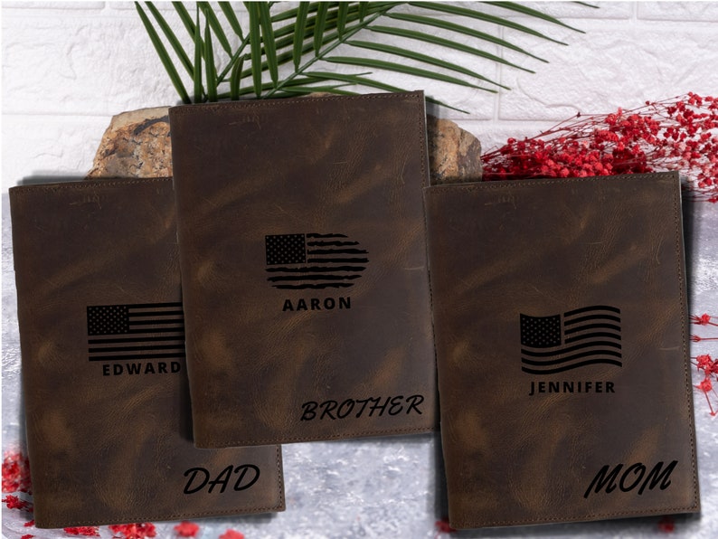 May include: Three brown leather journals with an American flag design and personalized names. The journals are labeled "Dad", "Brother", and "Mom".