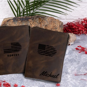 May include: Two brown leather journals with distressed finishes. Each journal features a black and white American flag design and a personalized name. The names are "Robert" and "Michael".