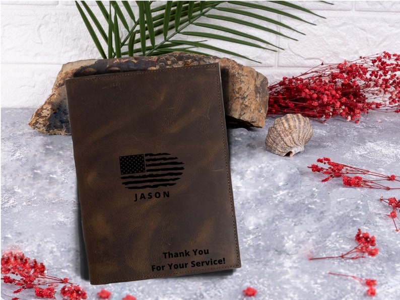 May include: A brown leather journal with a distressed look. The cover features an engraved American flag, the name "JASON", and the text "Thank You For Your Service!"
