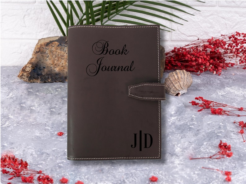 May include: A brown leather journal with the words "Book Journal" embossed on the front cover. The initials "J.D." are also embossed on the front cover.
