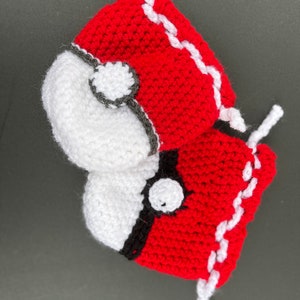 May include: Two crocheted Poke Balls, one red and white and one red and black, with white crocheted strings.