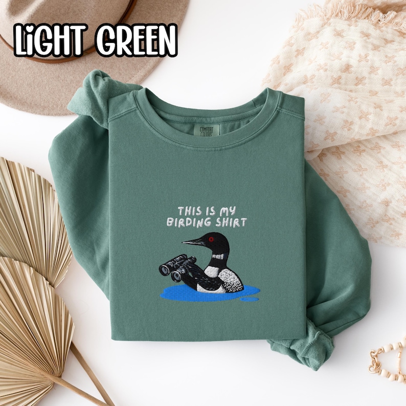 双眼鏡を持ったアビの刺繍入りバードウォッチングシャツ スウェットシャツ 野生動物の湖のシャツ 鳥好きの方へのギフト Light Green