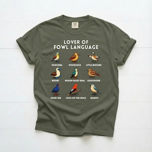 May include: A white ceramic mug with a black handle and the text "But First, Coffee" in a bold, black font. The mug is set against a blurred background, suggesting a cozy setting.