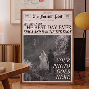 May include: A framed newspaper print with the headline "THE BEST DAY EVER" and the names "ERICA AND DAN." The print includes a black and white photo of a couple and the text "YOUR PHOTO GOES HERE."