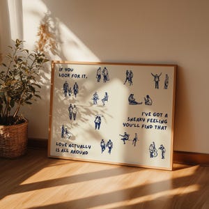 May include: A framed print with a light beige background and a wooden frame. The print features blue line drawings of people in various poses, with text that reads "If you look for it, Love actually is all around. I've got a sneaky feeling you'll find that."