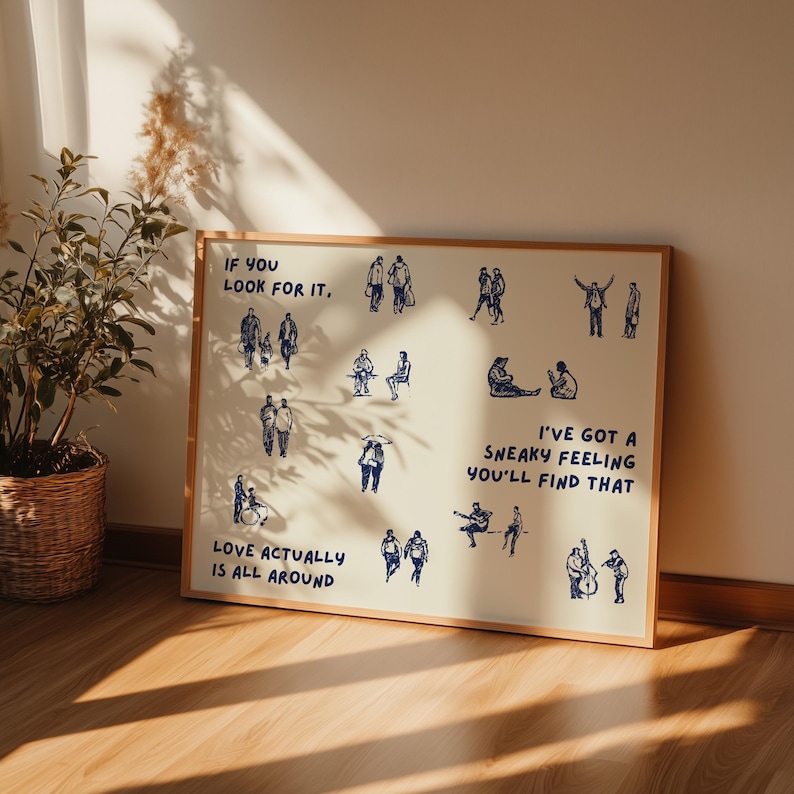 May include: A framed print with a light beige background and a wooden frame. The print features blue line drawings of people in various poses, with text that reads "If you look for it, Love actually is all around. I've got a sneaky feeling you'll find that."