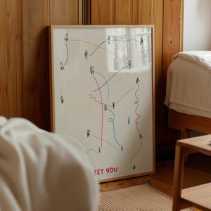 May include: A framed art print with a minimalist design showing small figures linked by colourful lines. The artwork includes the text "MEET YOU" at the bottom, set against a cream background. The frame is a light wood colour.