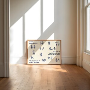 May include: A framed art print with a cream-colored background and a wooden frame. The print features blue line drawings of people in various poses, with text that reads "IF YOU LOOK FOR IT," "LOVE ACTUALLY IS ALL AROUND," and "I'VE GOT A SNEAKY FEELING YOU'LL FIND THAT."