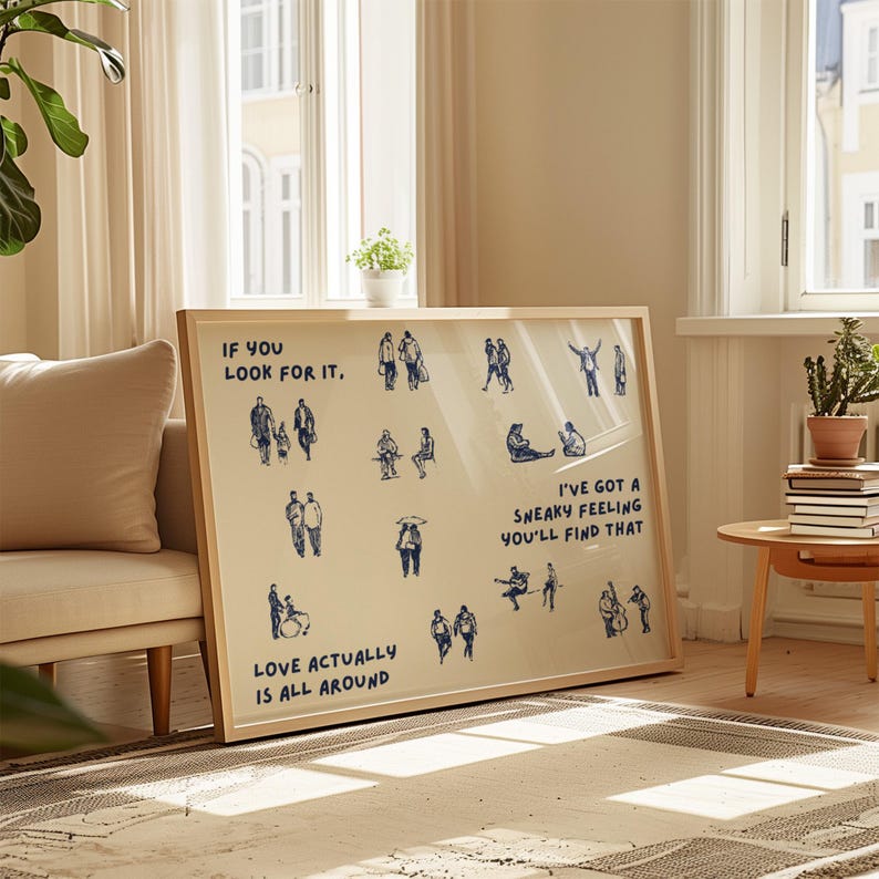 May include: A framed art print with a beige background and blue illustrations of people. Text includes "If you look for it," "Love actually is all around," and "I've got a sneaky feeling you'll find that."
