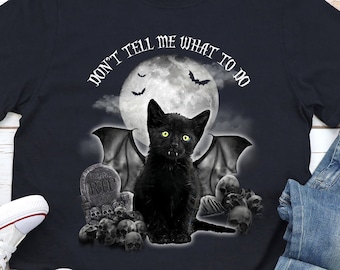 May include: A black t-shirt with a black cat with bat wings in front of a full moon. The text "Don't tell me what to do" is written in a circle around the moon.