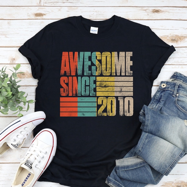 May include: A black t-shirt with a vintage-style graphic that says "Awesome Since 2010" in colourful block letters.