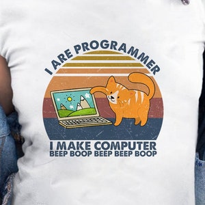 Peut inclure: T-shirt blanc avec un graphique rétro d'un chat utilisant un ordinateur portable. Le texte dit "I are programmer I make computer beep boop beep beep boop".
