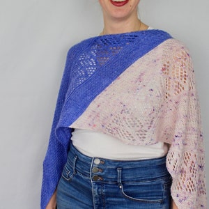 Può includere: Una donna indossa uno scialle di maglia blu e rosa con una camicia bianca e jeans blu.