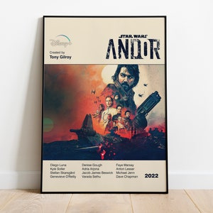 以下が含まれることがあります： スター・ウォーズシリーズ「Andor」のポスター。宇宙船の前でキャラクターのグループが描かれている。ポスターは黒い額縁に入っていて、赤、オレンジ、青の色合いで構成されている。「STAR WARS ANDOR」の文字は黒地に白で書かれている。右下には2022年と記されている。