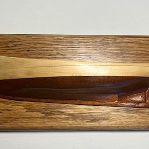 May include: A wooden plaque with a carved model of a Muscongus Bay lobster boat named "Ranger" built in 1939. The plaque is made of oak wood and has a dark brown stain.