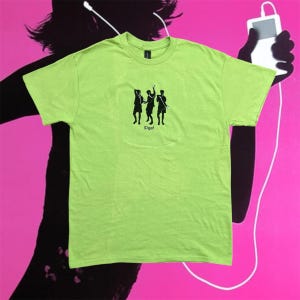 Pode incluir: Uma t-shirt verde-limão com um gráfico preto de três figuras dançando e o texto "IDgaf" abaixo. A t-shirt está sobre um fundo rosa com a silhueta de uma pessoa ouvindo música.