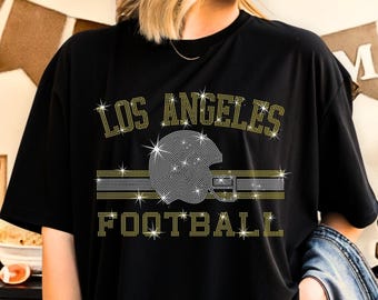 Op de afbeelding: Zwart T-shirt met een strass-ontwerp met de woorden "Los Angeles Football" en een voetbalhelm.