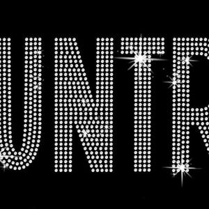 May include: The word "CUNTRY" in sparkling white rhinestones, with a star on each side, set against a black background. The letters are large and bold, with a slight sparkle effect.