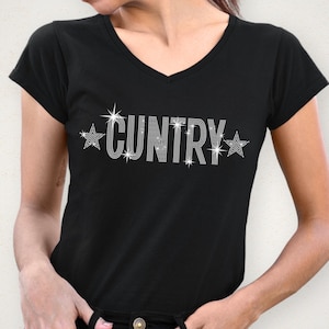 May include: Black V-neck t-shirt with the word "CUNTRY" spelled out in sparkling rhinestones. The word is flanked by starburst designs. The shirt is a short-sleeved style.