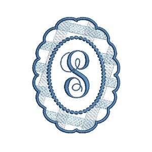 Op de afbeelding: Een geborduurd monogram van de letter "S" in een blauw-wit ruitpatroon, omlijst door een geschulpte ovale rand. De letter is in een cursief lettertype en de rand is omlijnd met een kralenontwerp.