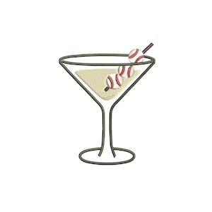 May include: A martini glass with a baseball theme. The glass is outlined in dark green, filled with a light beige liquid, and garnished with three baseball-shaped olives on a dark brown swizzle stick. The background is white.