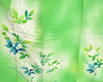 May include: A green silk fabric with a white floral pattern. The flowers are delicate and have a soft, watercolor-like appearance. The fabric has a subtle sheen and a smooth texture.