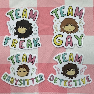 May include: Four colorful stickers with cartoon characters and text. The stickers say "Team Freak", "Team Gay", "Team Babysitter", and "Team Detective".