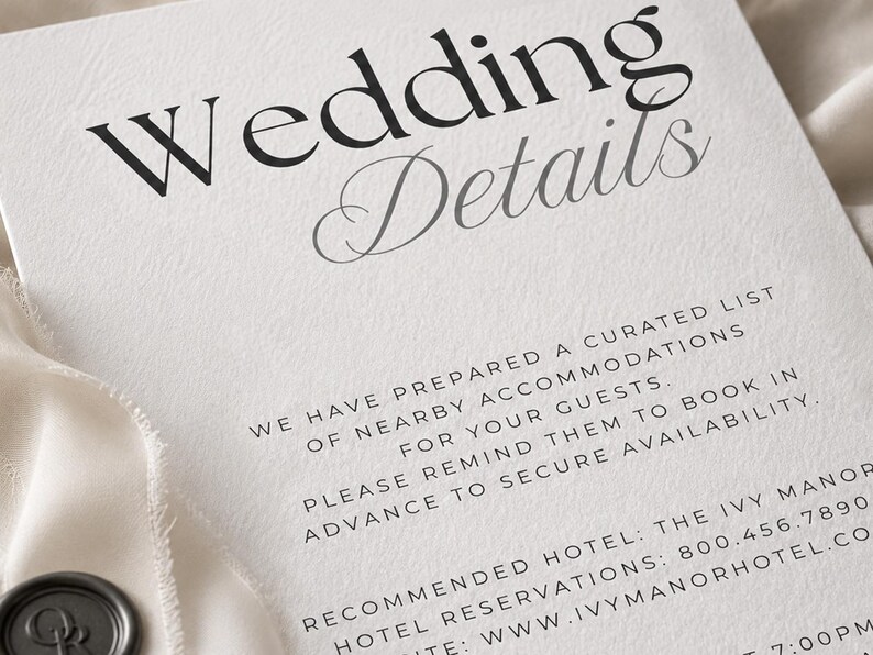 May include: A white card with black text reading Wedding Details, followed by information about nearby accommodations, a recommended hotel, and contact details. The card features a textured surface and a dark grey wax seal in the corner.