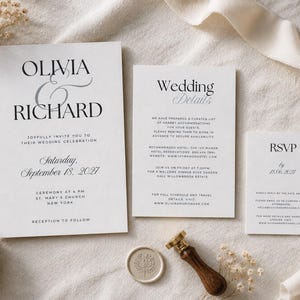May include: A white wedding invitation suite featuring black serif typography with the names Olivia and Richard, a separate details card, and an RSVP card. A wax seal with a botanical design and a wooden handle stamp are placed next to the cards.