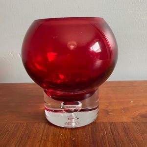 Peut inclure: Un photophore en verre rouge vif. La partie supérieure est sphérique, tandis que la base est en verre transparent. Ce photophore est conçu pour une petite bougie et convient à la décoration intérieure.