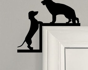 May include: Black silhouette of a dachshund dog looking up at a German Shepherd dog silhouette. Both dogs are on a white door frame.