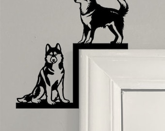 May include: Two black silhouette husky dog wall decor pieces mounted on a white door frame. The top dog is standing on a shelf and the bottom dog is sitting on a shelf.