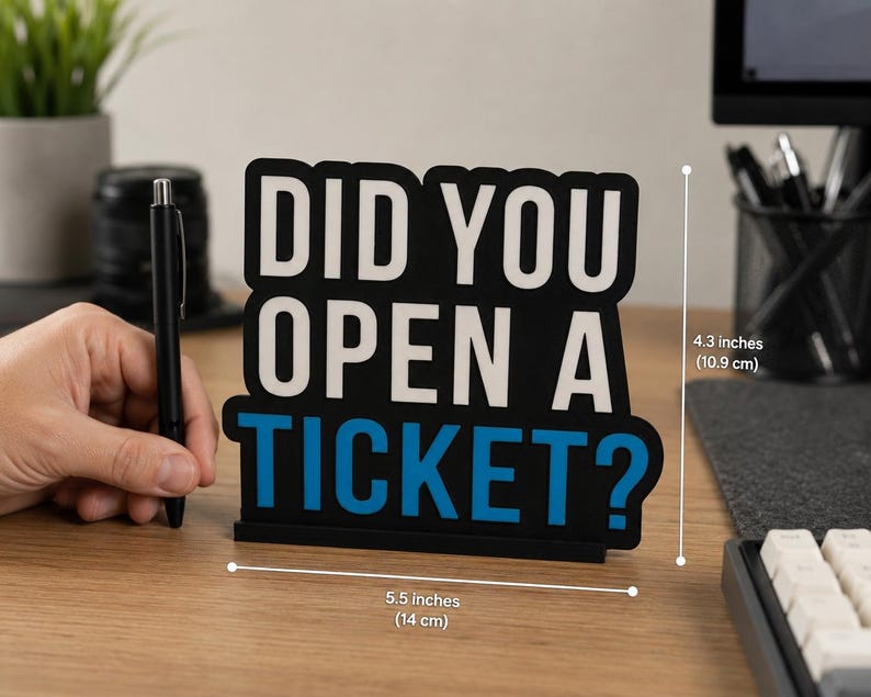 Puede incluir: Un letrero de escritorio negro con el texto "DID YOU OPEN A TICKET?" en blanco y azul. El letrero mide 14 cm de ancho y 10,9 cm de alto. Hay un bol&iacute;grafo negro al lado del letrero.