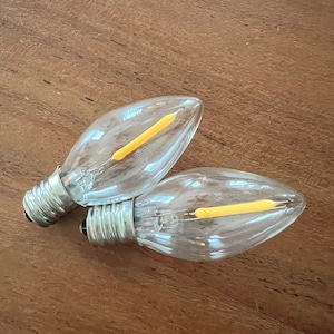 以下が含まれることがあります： 透明なガラス製の電球2個。電球の中は暖色系のLEDフィラメントが入っています。電球は標準的なねじ込み式で、さまざまな照明器具で使用できます。