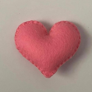 Op de afbeelding: Een roze vilten hart met een gestikte rand.