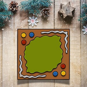 May include: A brown gingerbread cookie with a green frosting design and colorful sprinkles. The cookie is decorated with a white border and is on a wooden surface.