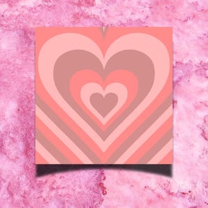 May include: A pink and brown heart-shaped design with concentric circles and stripes. The design is on a square background.