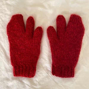 Puede incluir: Un par de guantes de punto rojos con textura peluda.
