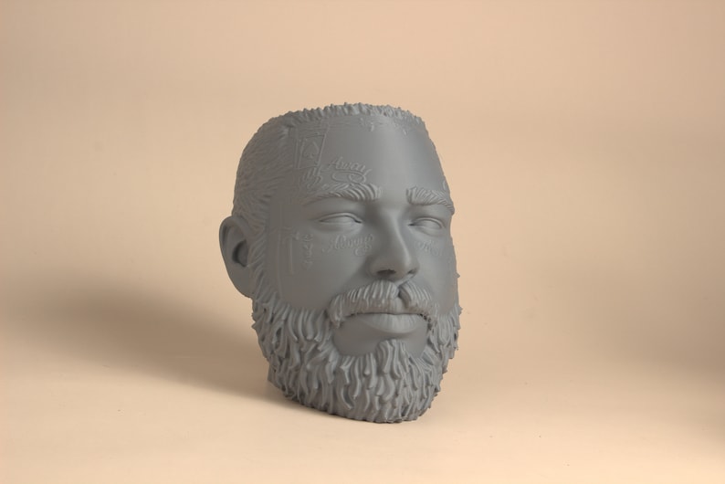 May include: A gray 3D printed bust of a person's head with a beard and a detailed design on the forehead.