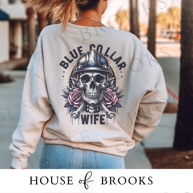 May include: A light gray sweatshirt with a blue collar wife graphic. The graphic features a skull wearing a hard hat and holding two wrenches. The skull is surrounded by pink roses.