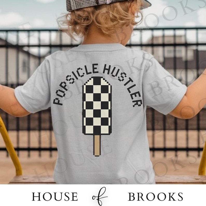 May include: A light gray t-shirt with the words "POPSICLE HUSTLER" arched above a pixelated popsicle design in black and white checkered pattern. The popsicle has a brown stick. The brand name "HOUSE of BROOKS" is at the bottom.
