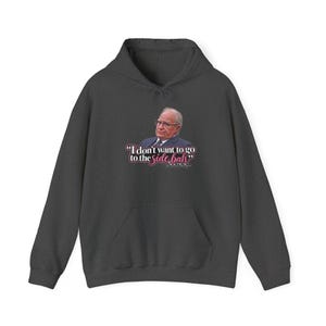 May include: A dark charcoal gray hooded sweatshirt featuring a graphic print of a person in a suit and glasses. Below the image, the text reads: "I don't want to go to the side bah" with the word "side" in white and "bah" in pink script.