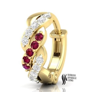 Puede incluir: Un aro de oro para la oreja con un diseño retorcido que presenta piedras preciosas rojas y blancas. El aro tiene un cierre con bisagra.
