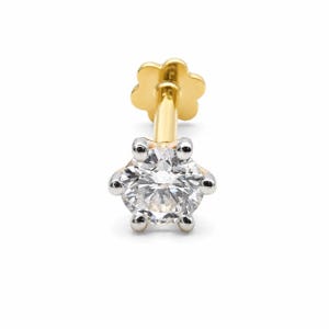 May include: A gold labret stud featuring a round, clear, faceted gemstone held in a six-prong silver-toned setting. The post is gold-colored and terminates in a flat, flower-shaped backing, providing a secure and decorative finish for this piece.