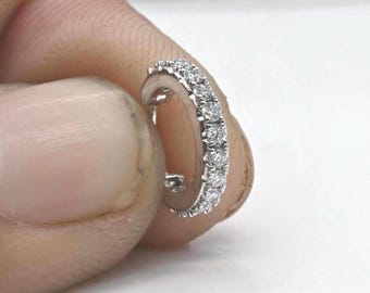 May include: A small, silver hoop earring with a single row of clear round diamonds set in a continuous line around the hoop.
