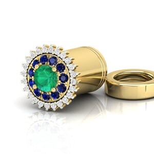 Può includere: Un orecchino rotondo dorato con uno smeraldo verde circondato da un'aureola di zaffiri blu e diamanti bianchi.
