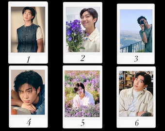 May include: A collage of six Polaroid photos featuring a man with dark hair. The photos show him in various settings, including a field of purple flowers, a city rooftop, and an indoor setting.